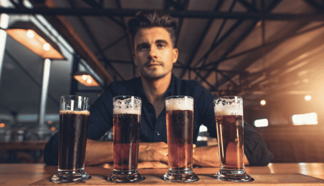 Craft brewer with a tasting paddle of four beers at a micro brewery – insured by Crafted Insurance