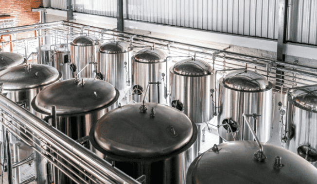 Large-scale stainless steel brewing tanks at a national craft brewery – covered by Crafted Insurance